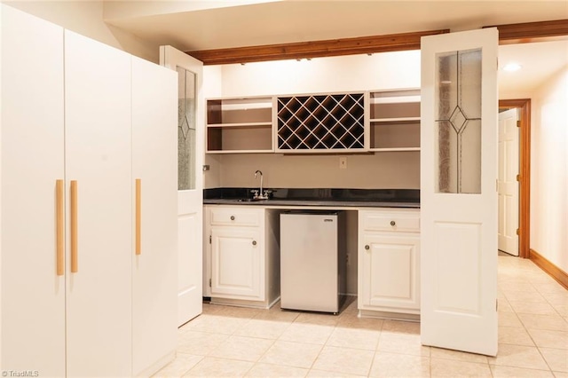 bar featuring refrigerator, indoor wet bar, a sink, and light tile patterned floors