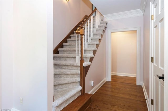 staircase featuring baseboards, ornamental molding, and wood finished floors