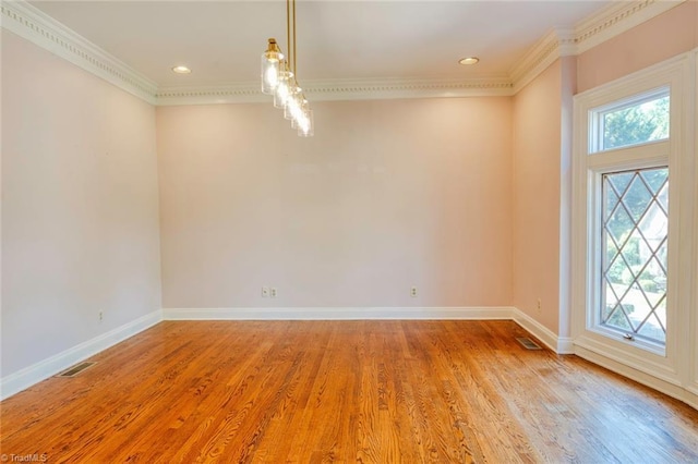 unfurnished room featuring baseboards, ornamental molding, visible vents, and light wood finished floors