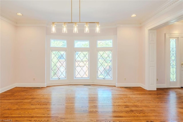 unfurnished dining area featuring wood finished floors, baseboards, and ornamental molding