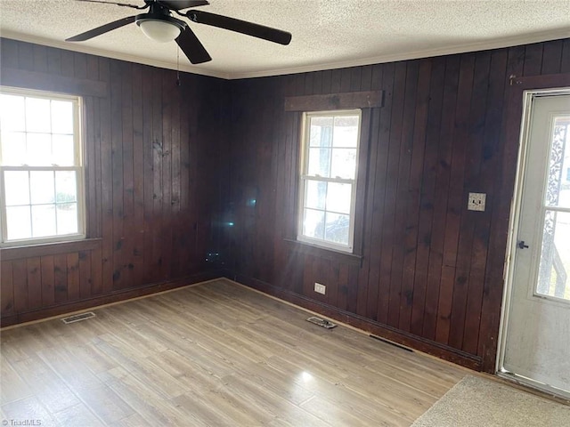 foyer entrance featuring ceiling fan, wood walls, crown molding, and light hardwood / wood-style flooring