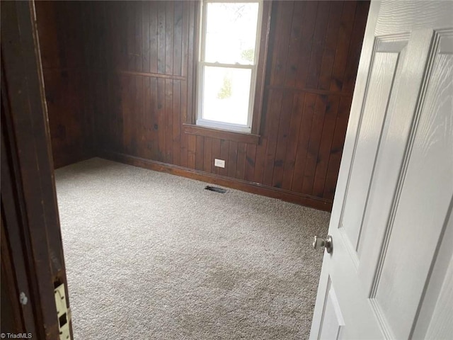 empty room with carpet floors and wood walls