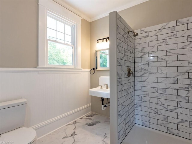 bathroom featuring toilet, ornamental molding, sink, and a tile shower