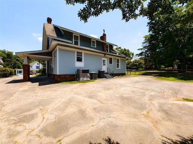 rear view of property featuring a carport and central AC