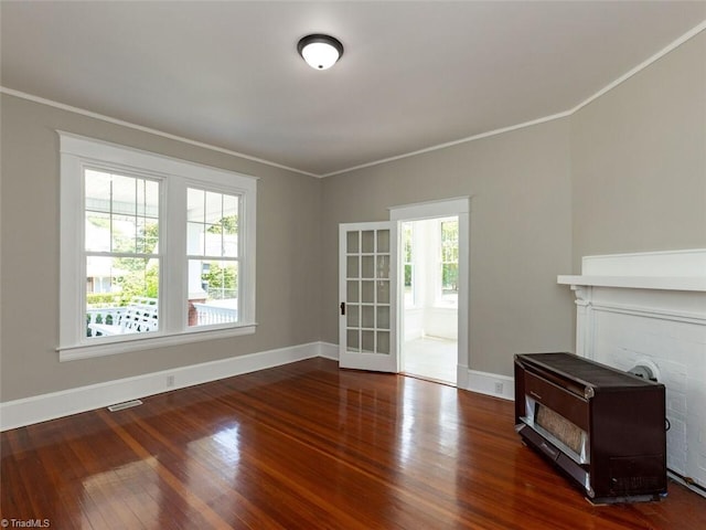 unfurnished living room featuring dark hardwood / wood-style flooring, ornamental molding, and a wealth of natural light