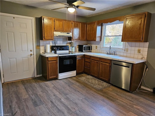 kitchen with sink, backsplash, dark wood-type flooring, and appliances with stainless steel finishes