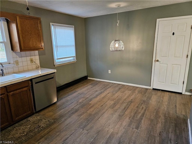 kitchen with pendant lighting, tasteful backsplash, sink, stainless steel dishwasher, and tile counters