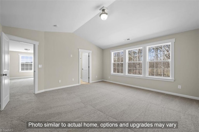 carpeted spare room featuring vaulted ceiling