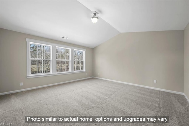 carpeted spare room with vaulted ceiling