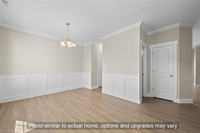 empty room featuring light hardwood / wood-style floors, an inviting chandelier, and ornamental molding