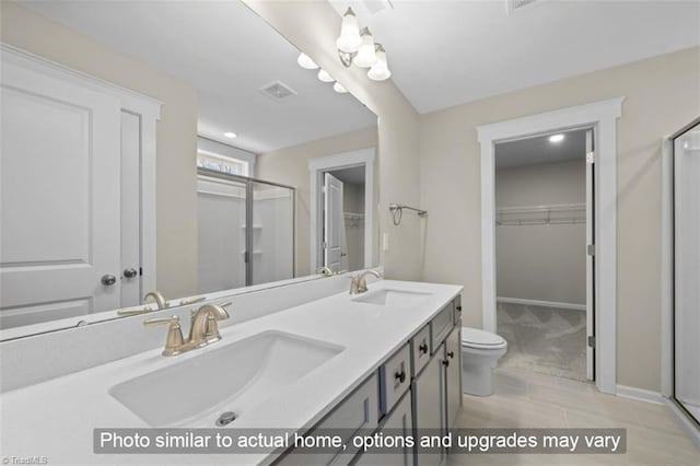 bathroom featuring a shower with shower door, vanity, and toilet