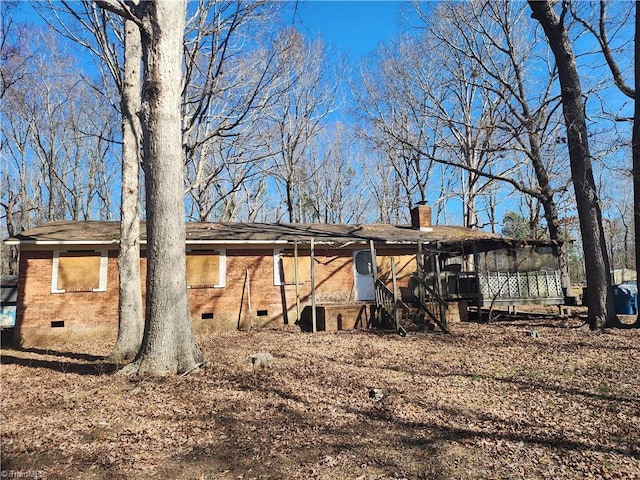 back of property featuring crawl space, brick siding, and a chimney