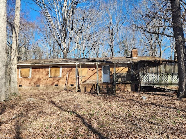 rear view of property featuring crawl space, a chimney, and a sunroom