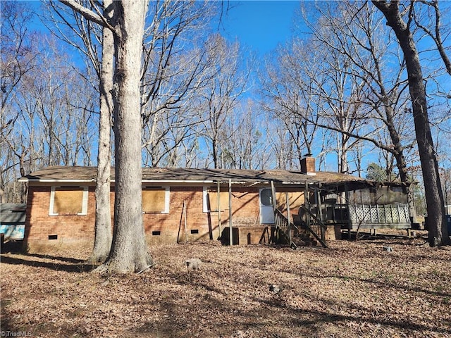 back of property featuring crawl space, brick siding, and a chimney