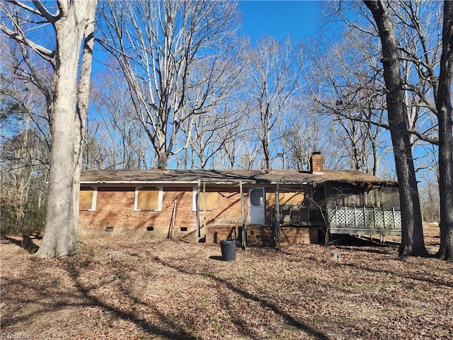 back of property with brick siding, roof with shingles, a chimney, a sunroom, and crawl space