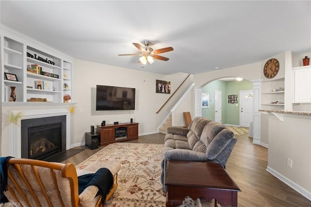 living room with dark hardwood / wood-style floors, ornate columns, and ceiling fan