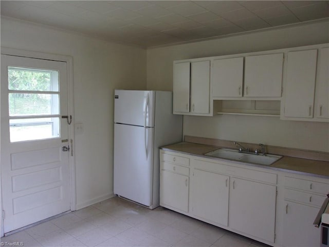 kitchen featuring white cabinets, sink, white refrigerator, and light tile floors