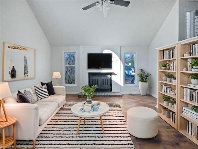 living area with baseboards, a fireplace with raised hearth, a ceiling fan, lofted ceiling, and dark wood-type flooring