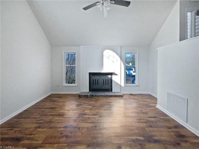 unfurnished living room with lofted ceiling, ceiling fan, visible vents, a brick fireplace, and dark wood-style floors