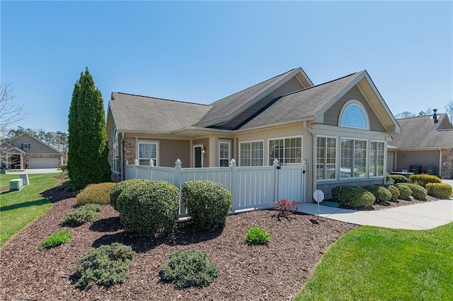 single story home featuring a sunroom, roof with shingles, fence, and a front yard