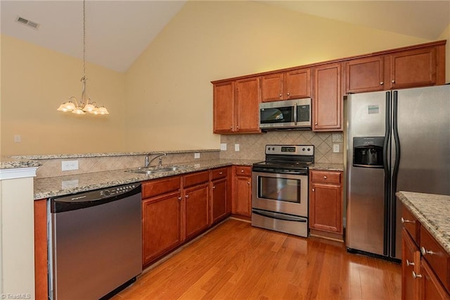 kitchen with brown cabinetry, visible vents, appliances with stainless steel finishes, light wood-type flooring, and a sink