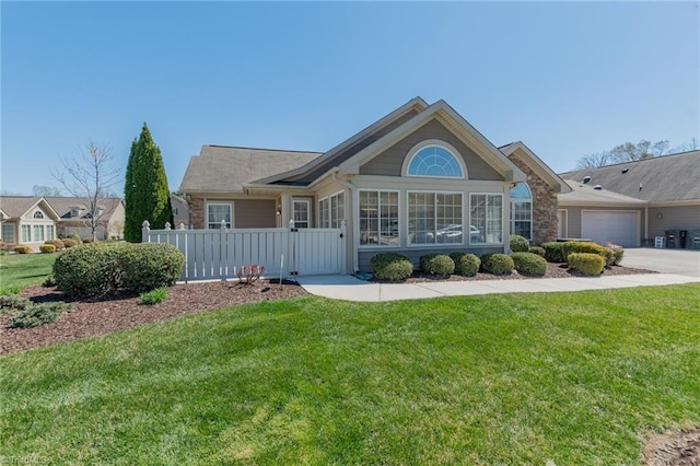 ranch-style home featuring concrete driveway, an attached garage, fence, and a front lawn