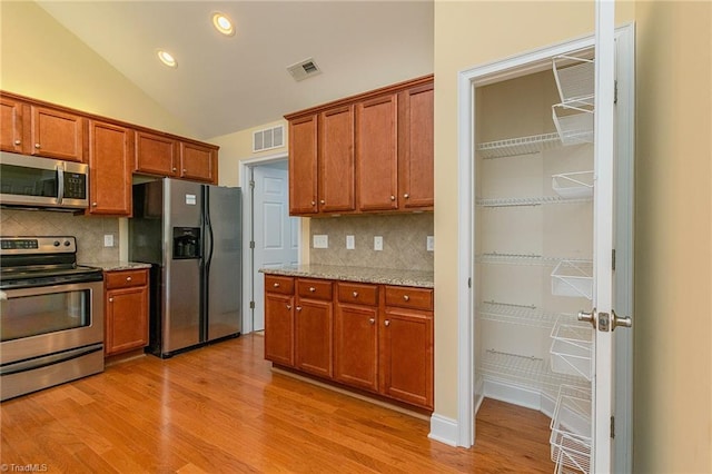 kitchen featuring decorative backsplash, brown cabinetry, visible vents, appliances with stainless steel finishes, and light wood finished floors