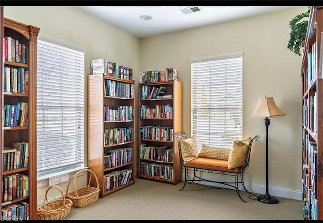 living area featuring carpet floors, bookshelves, and a wealth of natural light
