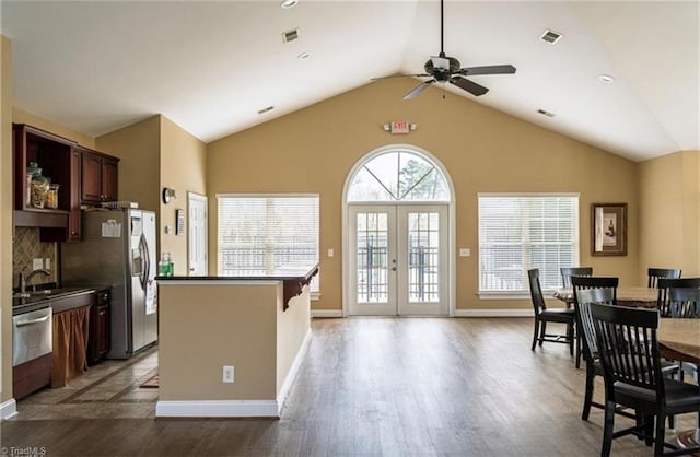 kitchen with wood finished floors, lofted ceiling, dark countertops, ceiling fan, and backsplash