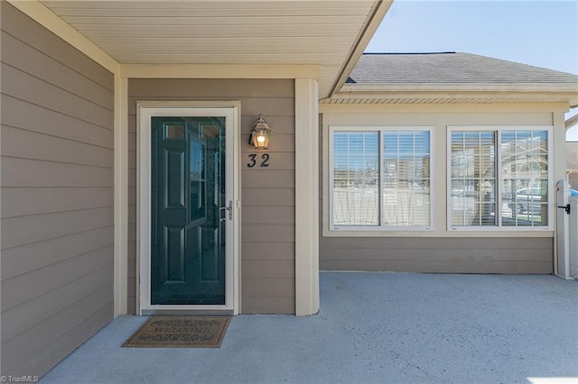 doorway to property with roof with shingles and a patio area