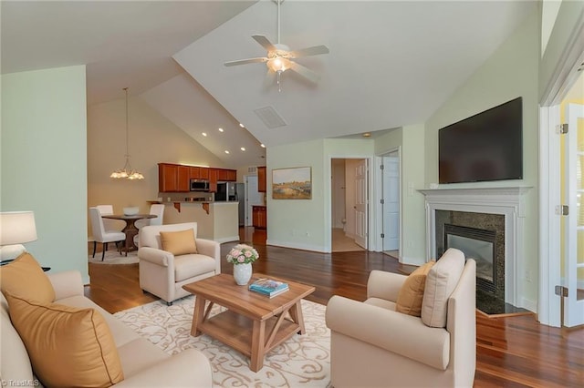 living area featuring visible vents, wood finished floors, a fireplace, high vaulted ceiling, and ceiling fan with notable chandelier