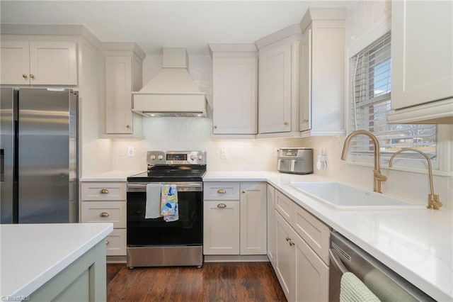 kitchen with stainless steel appliances, premium range hood, a sink, light countertops, and dark wood finished floors