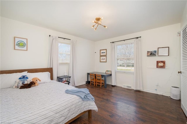 bedroom with an inviting chandelier, wood finished floors, visible vents, and baseboards