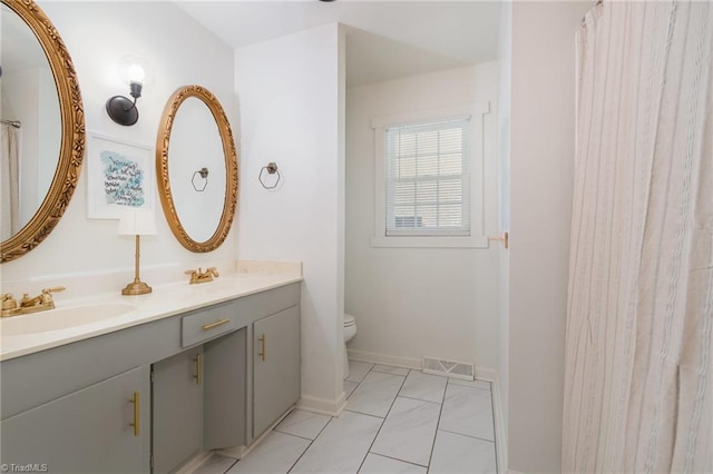 full bathroom featuring double vanity, visible vents, toilet, a sink, and baseboards