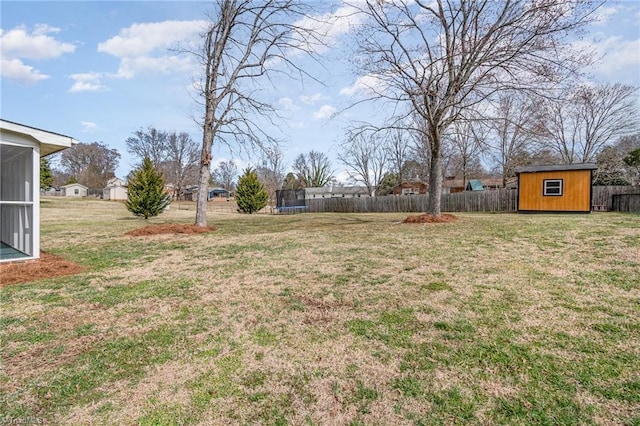 view of yard with a trampoline, an outbuilding, fence, and a storage shed