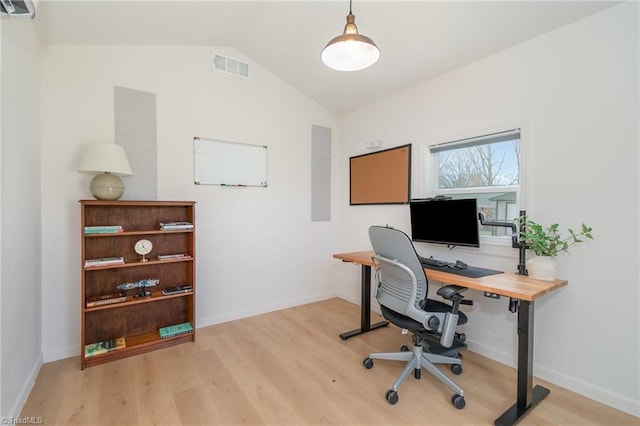 office with baseboards, visible vents, vaulted ceiling, and light wood finished floors