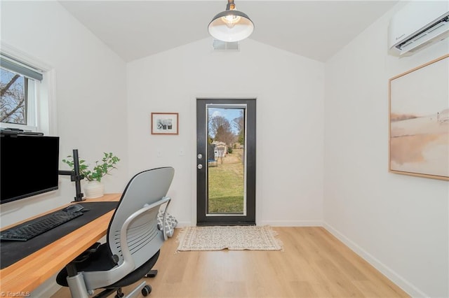 home office with visible vents, an AC wall unit, vaulted ceiling, wood finished floors, and baseboards