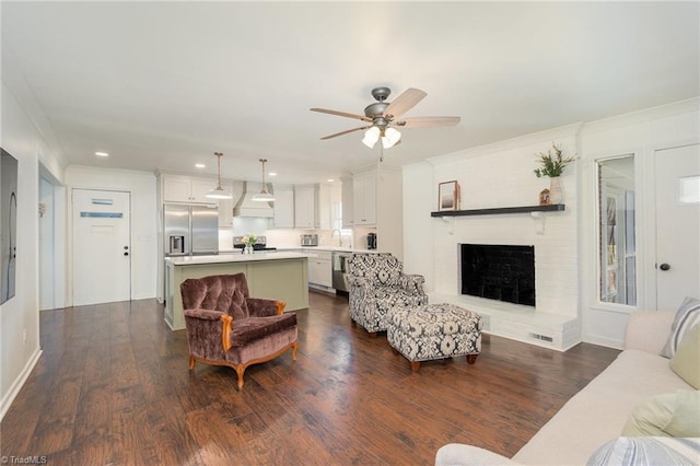 living room with a brick fireplace, dark wood finished floors, a ceiling fan, and recessed lighting