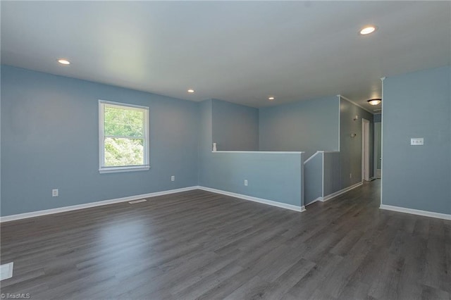 spare room with baseboards, dark wood finished floors, recessed lighting, and visible vents
