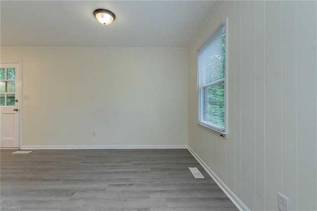 empty room with baseboards, visible vents, and wood finished floors