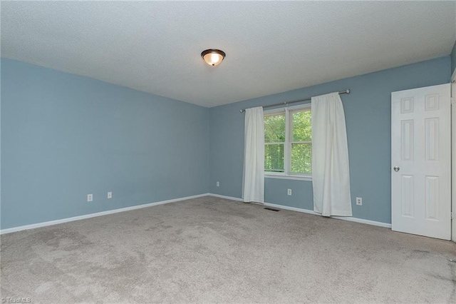carpeted empty room with a textured ceiling, baseboards, and visible vents