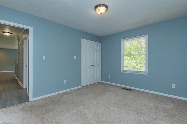 unfurnished bedroom featuring carpet, visible vents, baseboards, and a closet