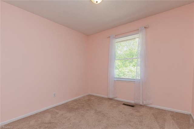 carpeted empty room featuring baseboards and visible vents