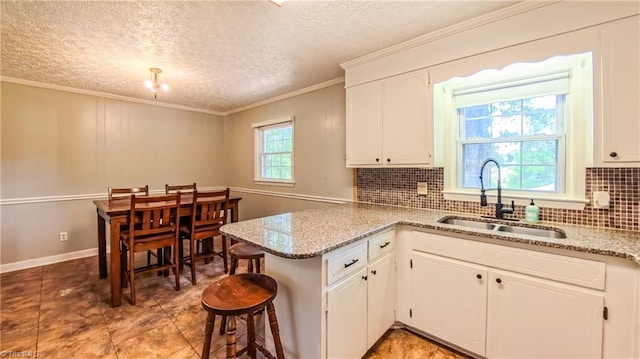 368 Shady Grove Rd, Eden, NC 27288 - kitchen featuring a peninsula, decorative backsplash, white cabinets, ornamental molding, and light stone counters