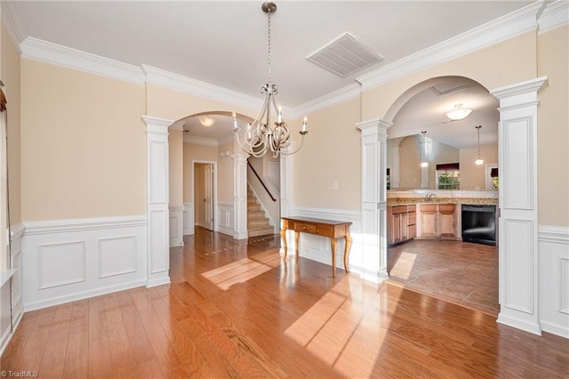 unfurnished dining area featuring hardwood / wood-style flooring, ornamental molding, and a chandelier