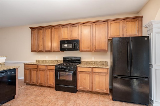 kitchen with light stone countertops and black appliances