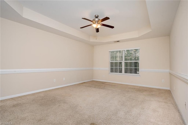 carpeted empty room with a tray ceiling and ceiling fan