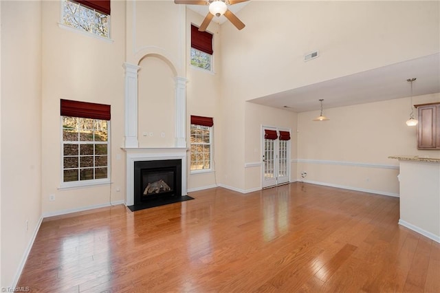 unfurnished living room featuring a healthy amount of sunlight, light hardwood / wood-style floors, and a high ceiling