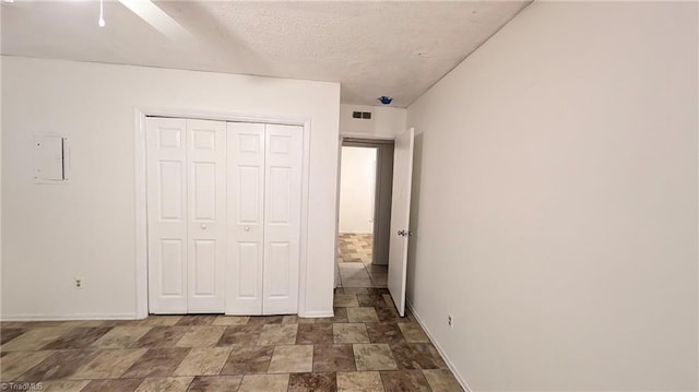 unfurnished bedroom with stone finish floors, baseboards, a closet, and a ceiling fan