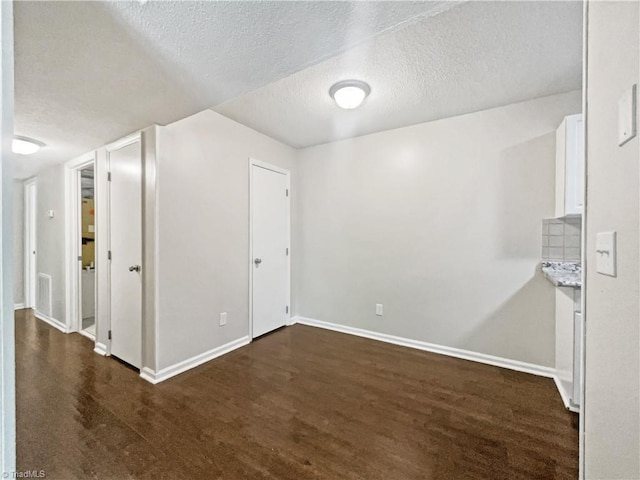 interior space with a textured ceiling and dark hardwood / wood-style floors